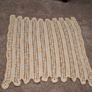 Handmade yellow and white crocheted baby blanket with a scalloped edge